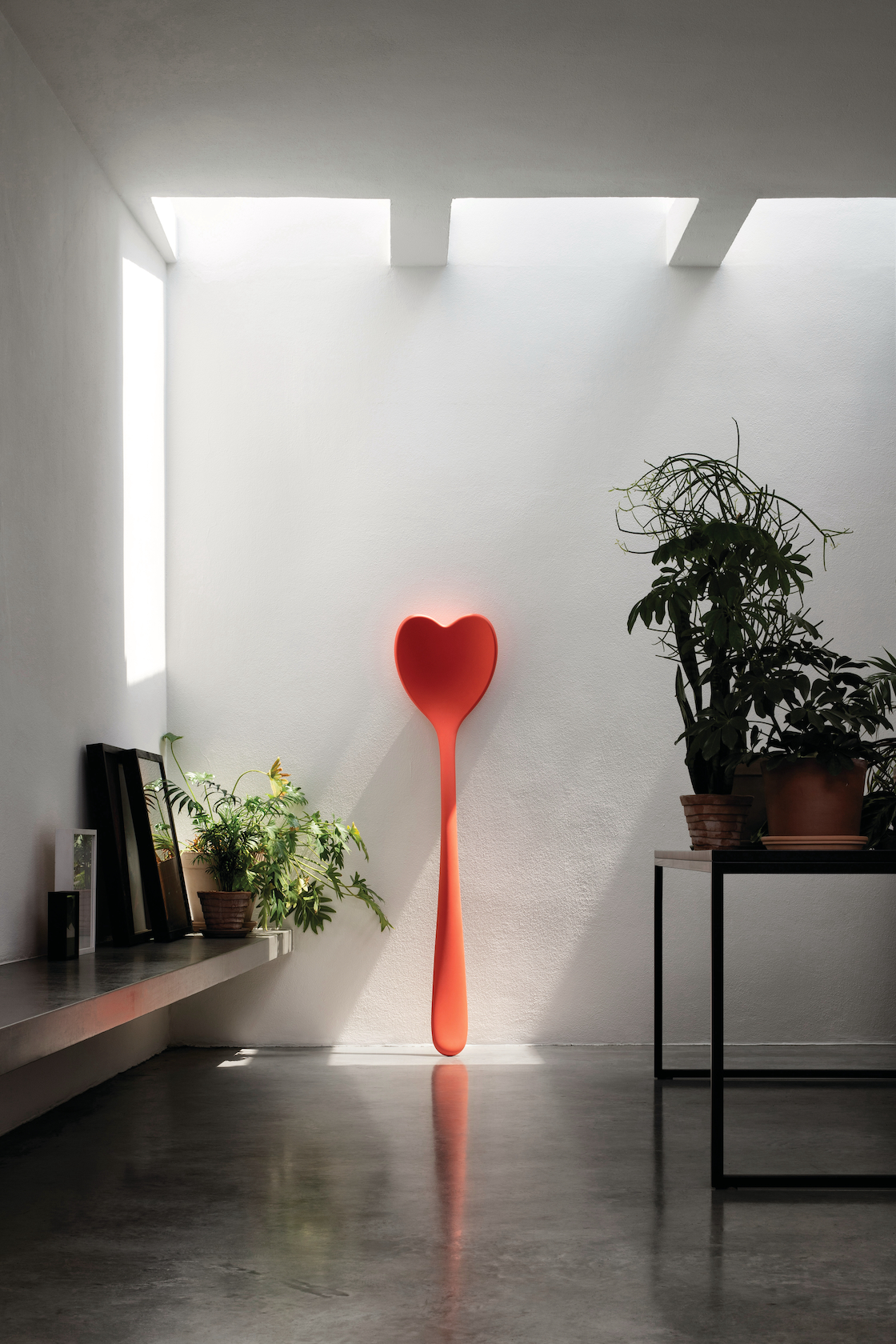 heart shaped spoon big sculpture setting indoor with plants and light from above
