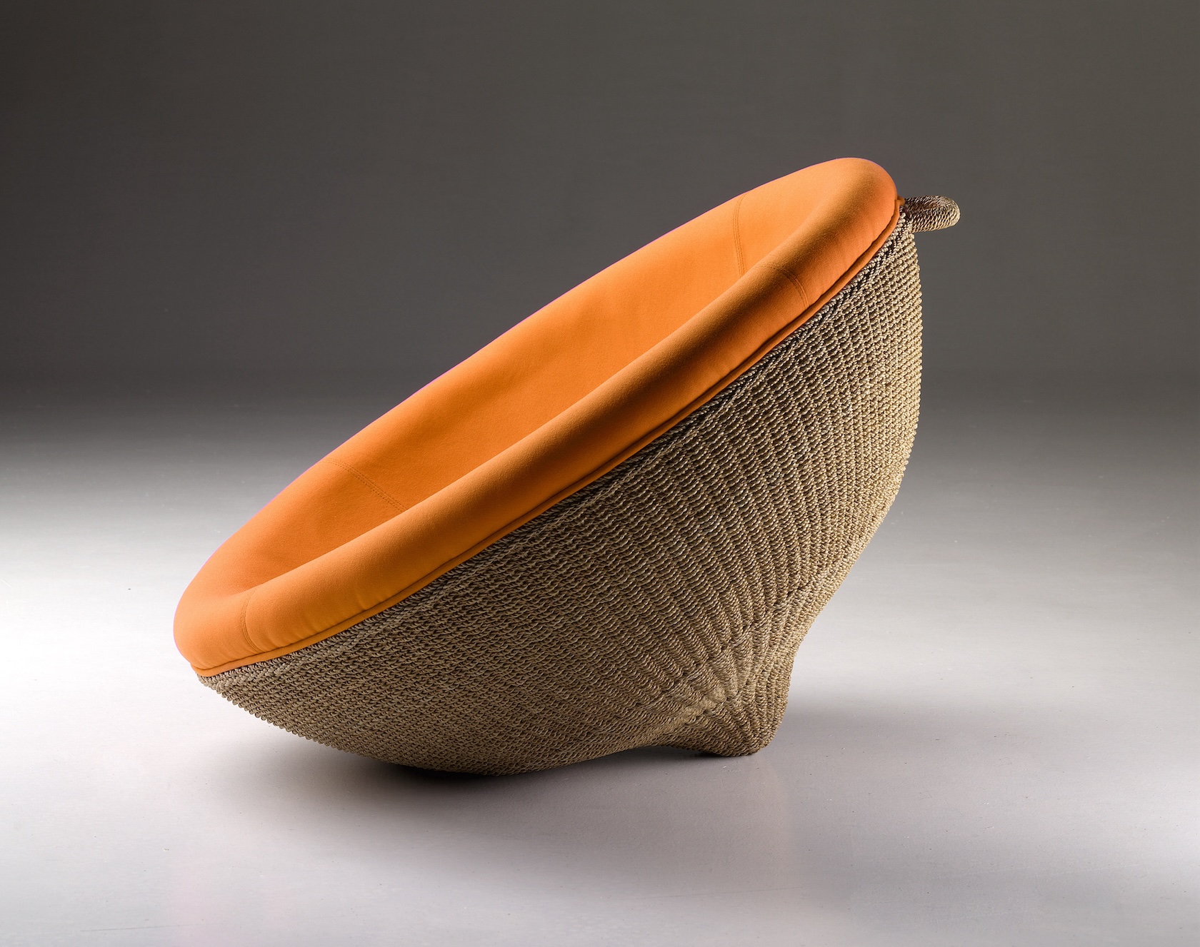 Fotografia poltrona LEM. Fotografia catalogo prodotto LEM arancione+rattan, di lato fondo grigio.